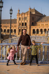 Obraz premium SEVILLE, SPAIN father and kids play outside Plaza Espana in Seville, Spain. It is a landmark example of the Renaissance Revival style in Spanish architecture..Important information