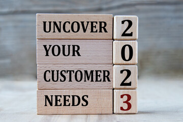 UNCOVER YOUR CUSTOMER NEEDS 2023 - words on wooden blocks on gray background