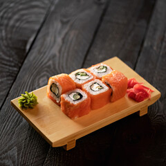 Set of Philadelphia sushi rolls on wooden board with soy sauce. Served with ginger and wasabi. Decorated with plant leaves on wooden board. Isolate on white background. View from above. 