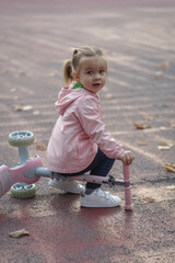 Child girl playing with a kids scooter