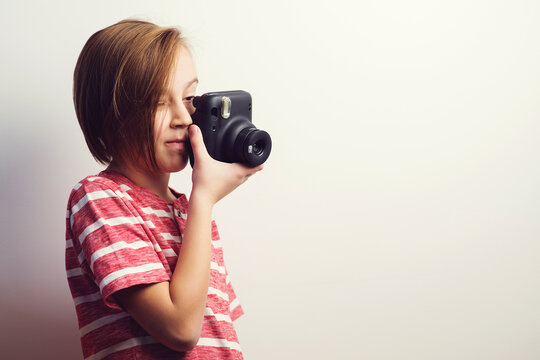 Boy having hobby to takes photo. Kid holding photo camera over grey background.