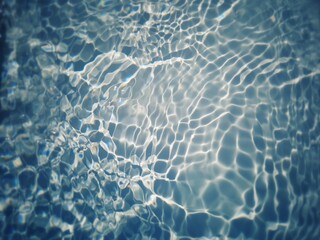 Obraz premium Defocus blurred transparent blue colored clear calm water surface texture with splashes and bubbles. Trendy abstract nature background. Water waves in sunlight with copy space. Blue watercolor shining