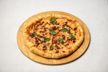 Traditional Italian pizza with minced meat, cheese and basil. Italian food on a wooden board. Isolate on white background. Copy space. Top view.