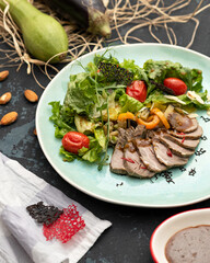 Sliced baked meat with vegetables on blue plate. Serving dish. View from above. Dark background. Life style. 