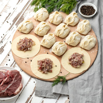 Manti On Wooden Cutting Board, Central Asian Cuisine. Manti Making Process. Demonstration Of Filling. Spices, Herbs On Wooden Table. Ready-made Semi-finished Products And Not Pinched. Top View. 