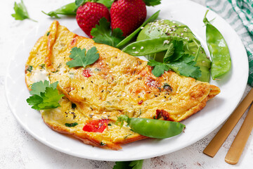 Omelette with tomatoes, feta cheese and avocado on white plate.