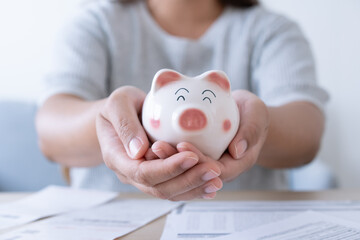 Obraz na płótnie Canvas Woman save money for household expenses in piggy bank.