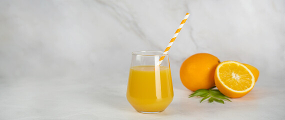 A light banner with copy space for text. A glass of freshly squeezed orange juice and delicious juicy oranges nearby. Healthy food and lifestyle, fruit bar