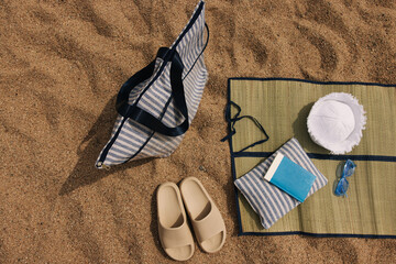 Fototapeta na wymiar Close-up of bag, panama hat, slippers, small pillow, blue sunglasses lie on lining. Summer things to take to beach.