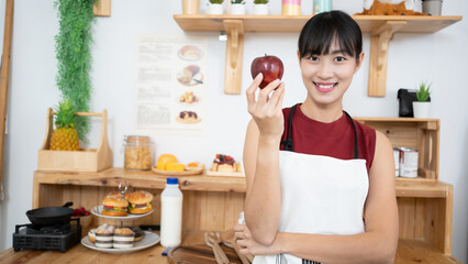 Asian attractive active woman pick up a red apple in kitchen at home.