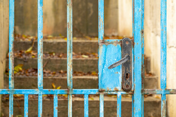 Lock and handle of the old shabby fence. Blue gate in the fence.