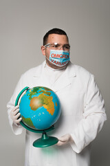 Scientist in medical mask with omicron variant lettering holding globe isolated on grey.