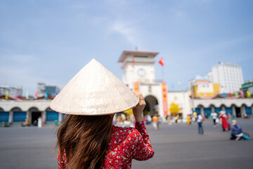 Vietnamese girl with Ao Dai dress walking in front of Ben Thanh market , Ho Chi Minh city, Vietnam....