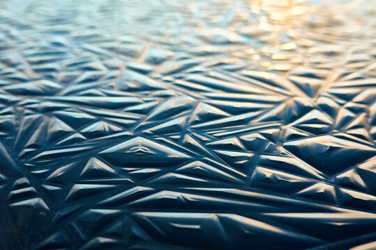 Cracked ice, dark water surface, frozen lake shore. Geometric natural pattern. Winter landscape, picturesque scenery. Concept image, graphic resources. Nature, ecology, climate, global warming