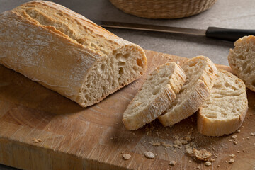 Traditional Italian fresh baked ciabatta bread and slices on a cutting board close up   - obrazy, fototapety, plakaty