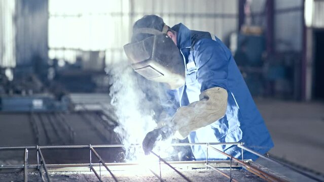 Professional welder works in a dark room with slow motion. Cinematic