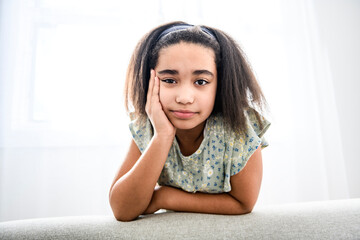 Pretty black child girl on sofa at home