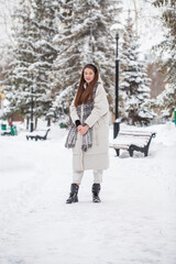 Fototapeta na wymiar Young beautiful woman in a gray down jacket in a winter snowy park