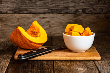 Sliced pumpkin in a white bowl on a wooden table.