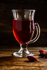 Rosehip tea in a glass cup on a wooden background.
