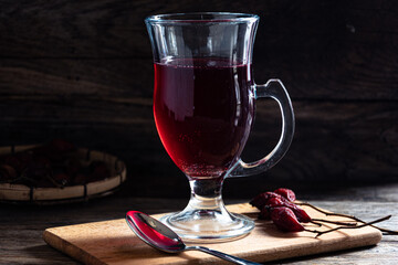 Rosehip tea in a glass cup on a wooden background.