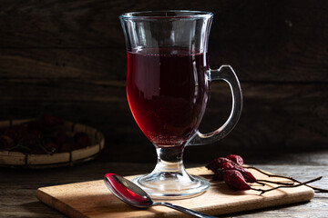 Rosehip tea in a glass cup on a wooden background.