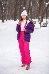 Young beautiful woman in a gray down jacket in a winter snowy park