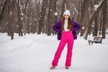 Fototapeta na wymiar Young beautiful woman in a gray down jacket in a winter snowy park