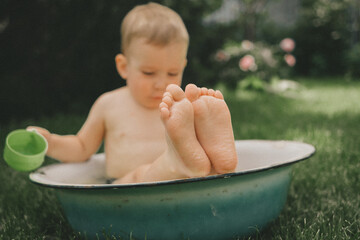 a child cools down in the heat in the summer in a basin in the backyard of the house