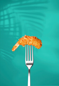 Fried shrimp in pank on a fork isolated on a blue background. Poster for a restaurant. Fried shrimp in pank