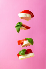 Vertical view of a flying caprese salad and pink background