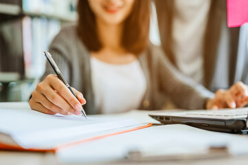 Asian woman students are reading and discussing about exam preparation. presentation, study for test preparation in library.Education, Learning, Student, Campus, University, Lifestyle concept.