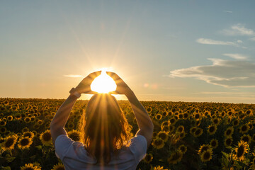 Girl in a field of sunflowers looking at the sun horizontally