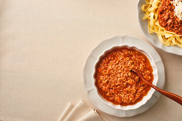 A bowl of fresh BOLOGNESE SAUCE and a plate of fresh tagliatelle pasta with bolognese sauce. Copy space. Top view.