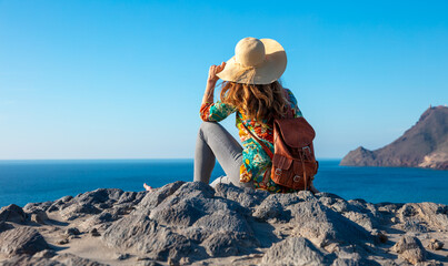 Woman sitting on rock against sea
