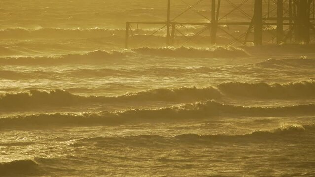 Slow motion waves around base of ruined Brighton west pier, evening light