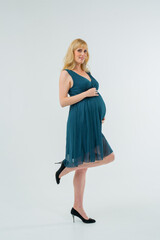 Naklejka premium A beautiful pregnant girl poses in the studio
