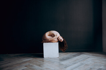 Beautiful, natural naked girl artistic posing at a stylish and fashionable nude photo shoot as a model in a photo studio with a transparent cape and bandage and looks like art