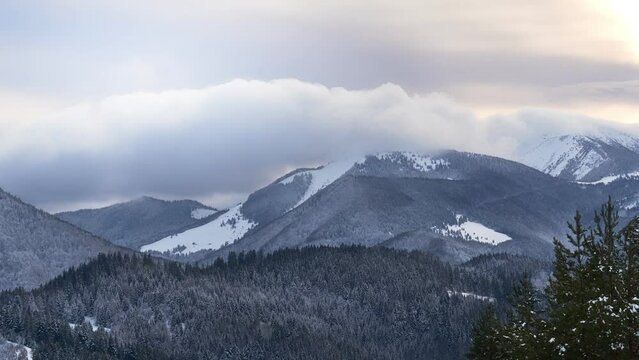 Clouds moving over the mountains during twilight in winter landscape. Tiemlapse