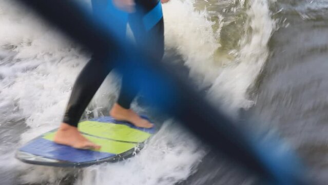 Man dressed in neoprene swimsuit wakesurfs following boat picking up high speed standing on board among waves in sea closeup