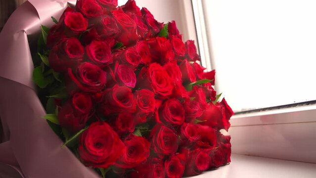 A huge bouquet of red roses on the windowsill. Valentine's Day.