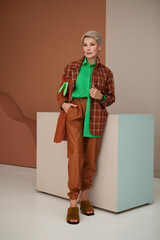 Mature fashion woman with short hair in stylish fashionable clothes, brown plaid jacket, bright...