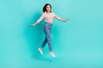 Fototapeta na wymiar Full length photo of pretty shiny lady wear pink shirt jumping hight walking isolated turquoise color background