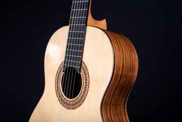 Fototapeta na wymiar Classical guitar top isolated on black background with a beautiful mosaic rosette, view from the top side. Beautiful Brazilian wood - Pau Ferro on the back and spruce on the top. 