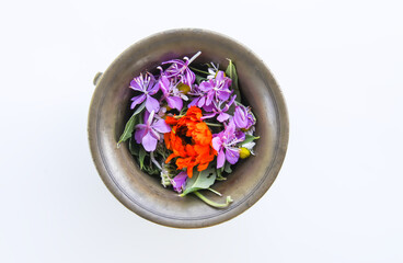Calendula and fireweed plants prepared for drying. Medicinal herbs and flowers in a cooper mortar.