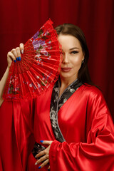 a girl in a red kimono with a red fan on a red background