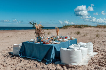 Delicious food and flowers for outdoor summer picnic. Lunch on the beach by the sea. Picnic in the style of boho.