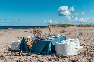 Delicious food and flowers for outdoor summer picnic. Lunch on the beach by the sea. Picnic in the style of boho.