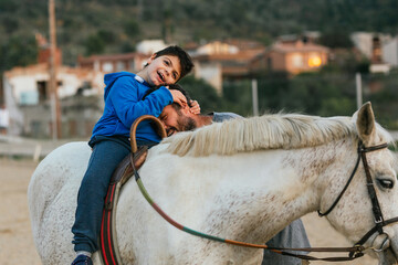 Disabled boy hugging his physiotherapist during equine therapy session