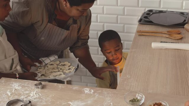 African American grandmother with two tween kids baking homemade cookies together at kitchen